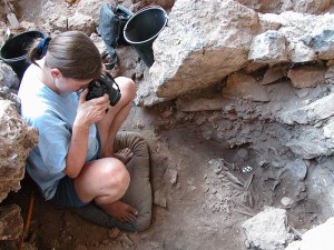 <p>Natalie Munro, associate professor of anthropology, photographing a grave thought to be that of a shaman at the archaeological site of Hilazon Tachtit Cave in northern Israel. Photo by Gideon Hartman</p>