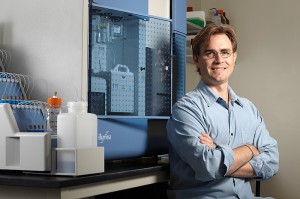 <p>Brenton Graveley, associate professor of genetics and developmental biology, with the Illumina Genome Analyzer, a new instrument for sequencing genetic material. Photo by Lanny Nagler</p>