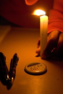 <p>A Metanoia button is lit by candlelight during the "What Will You Do?" rally. At the same table, students signed a declaration stating how they will act to prevent sexual assault, during a rally titled "What Will You Do?"</p>