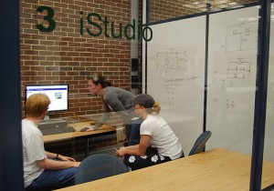 <p>Students work together in a group study room, known as an iStudio, in the Learning Commons.</p>
