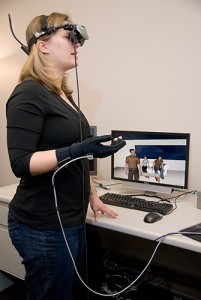 <p>Marcy Boynton, a psychology Ph.D. student, models the virtual reality headset and glove in the Advanced Interactive Technology Center at CHIP. Photo by Jessica Tommaselli</p>