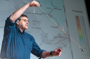 <p>Vernon Cormier, professor of physics, demonstrates how the sway of buildings in an earthquake can be likened to an updside-down pendulum motion. Photo by Frank Dahlmeyer</p>