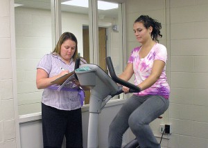<p>Brittany West (on bike), a resident of Mansfield, receives physical therapy for an injured knee from Maryclaire Capetta, a physical therapist at the Nayden Rehabilitation Clinic. Photo by Janice Palmer</p>