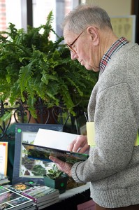 <p>An attendee at the 8th annual Garden Conference peruses gardening books for sale. Photo by Daniel Buttrey</p>
