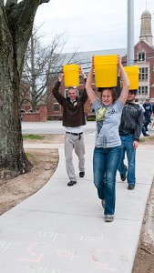 <p>Students led by Brenna Regan, a sophomore anthropology major, raise money and awareness for NURU, an organization that works to end extreme poverty. The event was titled Bring Hope to Her, and the buckets of water were carried to foster awareness of the five gallon buckets of water many women in Kenya carry on their heads for 20 hours a week from age 5 onward. Photo by Frank Dahlmeyer</p>