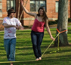<p>Ryan Wheeler, a physiology and neurobiology graduate student, helps Eileen Underwood, a junior environmental science major, balance on a slackline outside the South Campus residence halls. Photo by Jessica Tommaselli </p>