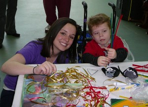 <p>Eileen Semancik encourages a young Shriners patient during an arts and crafts session. Photo supplied by the Office of Community Outreach</p>