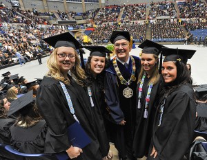<p>President Michael Hogan poses for a photo with graduates at the CLAS Commencement ceremony at Gampel Pavilion. Photo by Peter Morenus</p>