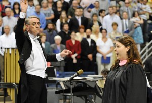 <p>Rachel Binaco sings the National Anthem during  Graduate Commencement ceremony at Gampel Pavilion. At left is Jefrey Renshaw, conductor of the University Wind Ensemble. Photo by Peter Morenus</p>