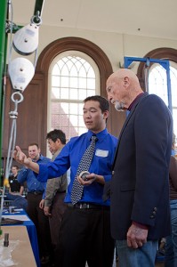 <p>Mechanical Engineering senior Erik Kong discusses a bearing testing unit with alumnus Richard Gamble (Electrical and Mechanical Engineering, '49). Mr. Gamble, now retired, is a former president and CEO of Colt Industries and a former executive with Hamilton Standard (now Hamilton Sundstrand).  Erik and fellow student Stephen Symski (ME) developed the "Metering Tank Bearing Failure & Design Analysis" project for Rogers Corporation. The project captured second prize and $1,000 in a juried competition among Mechanical Engineering seniors. The students presented their prototype during the School of Engineering's Senior Design Demonstration day held in the Wilbur Cross building on Friday, April 30. Photo by Christopher LaRosa</p>