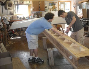 <p>Undergraduates Peter Omdahl and Jon Turban add a construction platform to pieces that will become the strongback, or the bottom, of the boat. Photo by Bill Armitage </p>