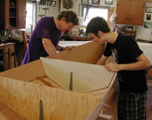 <p>Photo of two Avery Point undergraduates doing a boatbuilding internship with Bill Armitage of the John Gardner chapter of the Traditional Small Craft Association. Photo by Christine Buckley </p>