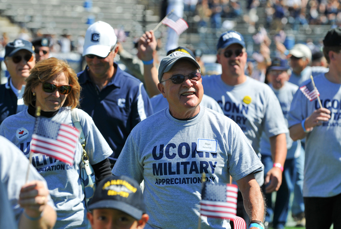 <p>Ron Bernard '86, waves a flag at Rentscher Stadium as current and former military were recognized on the field. Photo by Peter Morenus.</p>