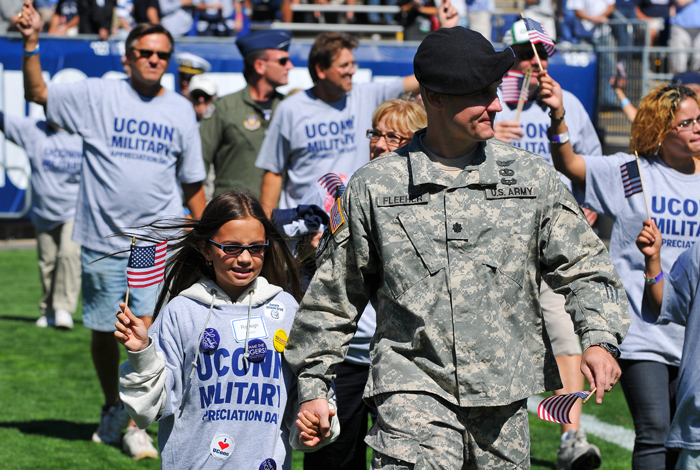 <p>Lt. Col. Scott Fleeher, professor of Military Science, walks with his daughter Reileigh, left, around the field at Rentscher Stadium as current and former military were recognized. Photo by Peter Morenus.</p>