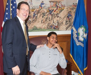 <p>Freshman Jeremy Lamb of the men's basketball team tries out Gov. Dannel Malloy's chair at the State Capitol. Photo provided by Athletic Communications</p>