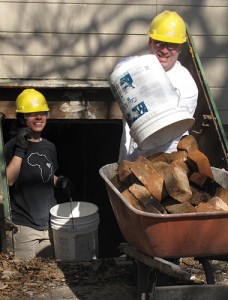 <p>Adam Pierce, from Avery Point, does some heavy lifting while Kaitlin Lastrina, from the Storrs campus, helps with the ‘bucket brigade’ of bricks that are being removed from the cellar of the house.</p>