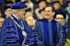 <p>The graduate commencement ceremony was held at Gampel Pavilion, where commencement speaker Gov. Dannel Malloy (right) shared a light moment with acting president Philip Austin.  Photo by Peter Morenus</p>