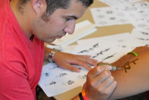 Tiago Machado, a graduate assistant in Student Activities applies a henna tattoo.