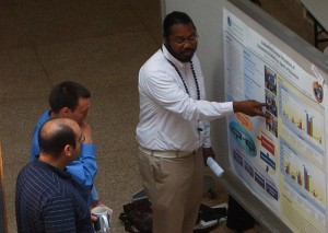 Ailton Coleman, who is pursuing a doctoral degree in public health, discusses his research with biomedical science students Brandon Albright and Kareem Mohni.