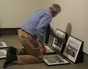 Benton Museum director Tom Bruhn is on his knees selecting photographs to be mounted for the faculty exhibition.