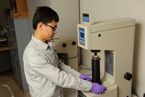 Jiang places a coated sample into a hardness tester. (Peter Morenus/UConn Photo)