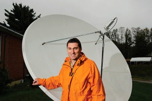 Emmanouil Anagnostou, professor of civil and environmental engineering,  stands near a satellite receiving dish. (Peter Morenus/UConn Photo)