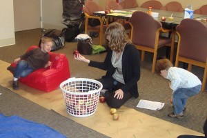 Intern Lindsay Dion engages a toddler with a basket of apples.