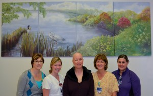 Treatment room nurses in the Neag Comprehensive Cancer Center with Karen Pergande, an artist and breast cancer patient, in front of the mural Pergande painted for the room. (Tina Encarnacion for UConn Health Center)
