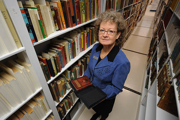 Terri Goldich, curator of the Northeast Children's Literature Collection, holds a copy of 'Black Beauty' while standing in the stacks at the Thomas J. Dodd Research Center. (Peter Morenus/UConn Photo)