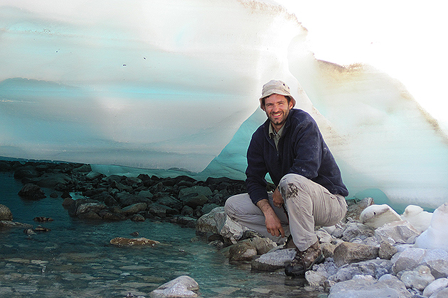 Mark Urban shown under a sheet of aufeis in Alaska. These ice sheets form over Arctic underground springs but have become less prevalent with global warming. (Photo courtesy of Mark Urban)