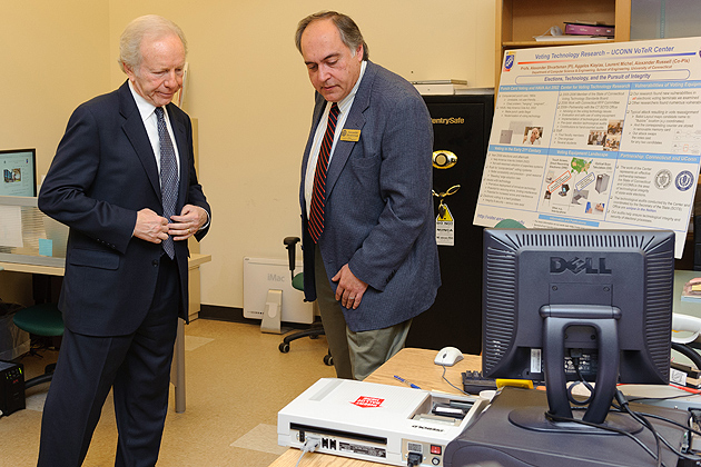Alexander Shvartsman, professor of computer science and engineering, shows Sen. Lieberman an example of an electronic voting device at the Center for Voting Technology Research. (Peter Morenus/UConn Photo)