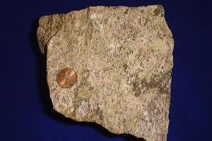Rare earth ore, shown with a United States penny for size comparison. (Wikimedia Commons Photo)