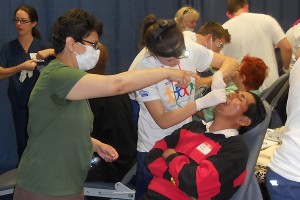 Dental student Christina Shaw (in white T-shirt) helps care for a patient on March 23, 2012. (Griffin Udelson for UConn Health Center)