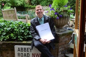 Music professor Kenneth Fuchs in the Abbey Road Studios garden in London, holding a score of his composition in honor of the S.S. United States. (Photo courtesy of Kenneth Fuchs)