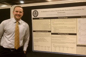 Scott McCarthy stands with a poster outlining his research. (Neag School of Education photo)