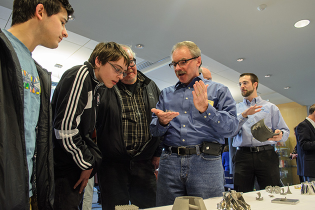 Howard Ellis, lab coordinator for computer science and engineering at UConn, right, explains how metal parts are created by additive manufacturing. (Ariel Dowski '14 (CLAS)/UConn Photo)