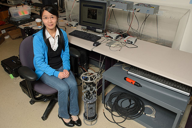 Zhaohui Wang, a Ph.D. candidate in engineering, next to the OFDM underwater modem in her lab. (Ariel Dowski/ '14 (CLAS)UConn Photo)