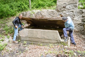 Nicholas Bellantoni, State Archaeologist, left, and Stuart Miller, professor of Hebrew, history, and Judaic studies, lift off the cover at the site of a former mikveh. (Peter Morenus/UConn Photo)
