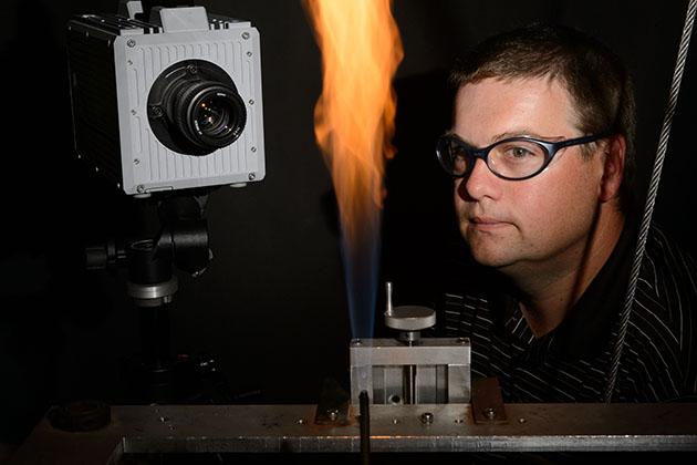 Michael Renfro, associate professor of mechanical engineering, observes a flame experiment in his lab. (Peter Morenus/UConn Photo)