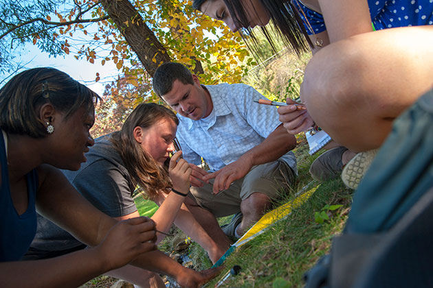 From left, Tiffany Cousins ’14, Kamilla Dynia ’14, Kevin Evringham (teaching assistant), and Victoria Chilinski ’16, look over water samples taken during an outdoor geography class introducing environmental processes and patterns, especially assessing change in environmental systems using spatial analysis techniques. (Sean Flynn/UConn Photo)
