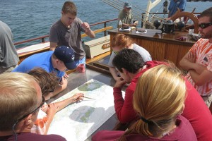 A crew member points to features on a nautical chart of Fishers Island Sound, which includes the Avery Point campus. Nautical charts are specialized tools used for navigation, published by NOAA. (Nathaniel Trumbull/UConn Photo)