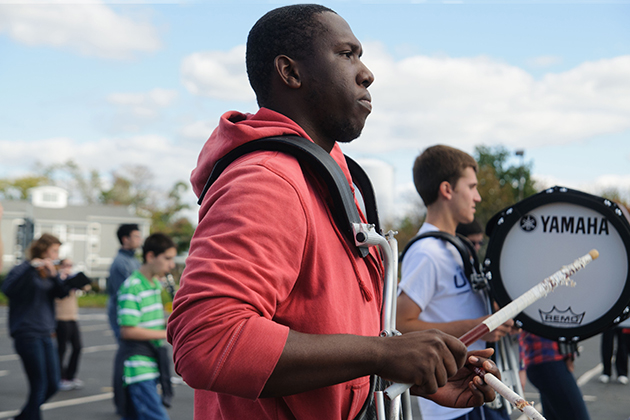 Devon Farquharson '15 (BUS) marches in formation with Stonington High School band students to help them with their performance. (Juanita Austin '15 (SFA)/UConn Photo)