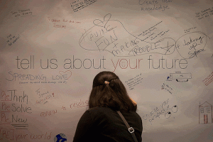 An attendee adds her entry to the "tell us about your future" poster at TEDxUConn on Sept. 21, 2013. (Photo by TEDxUConn)