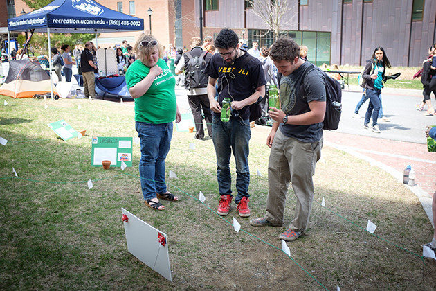 Sophie Marking '16 (CLAS), left, helps Thomas Chadwick '17 (CLAS) and Paul Ference '17 (ENG) determine their carbon "pawprint" as they navigate a maze during the UConn Earth Day Spring Fling held along Fairfield Way on April 22, 2014. (Peter Morenus/UConn Photo)