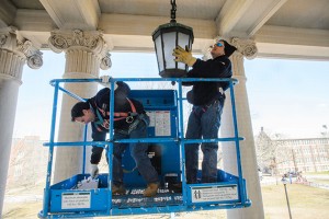 University electricians David Gawlak and Joesph Landry install blue lamps at the Wilbur Cross Building to raise awareness of autism. (Peter Morenus/UConn Photo)