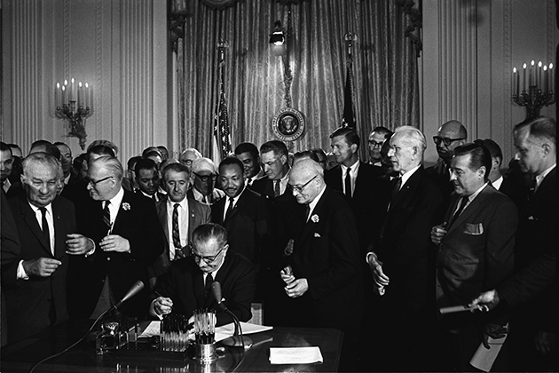 President Lyndon Johnson signs the Civil Rights Act at the White House in 1964. (Photo from the LBJ Presidential Library)