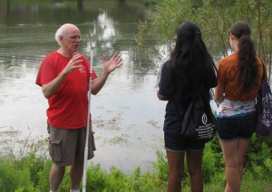 Dr. Kenneth Noll on the shores of Mirror Lake explaining biological collection techniques to KASET participants Sai Keerthi Manasanil and Hannah Leibowitz, both from South Windsor. (Sheila Foran/UConn Photo)