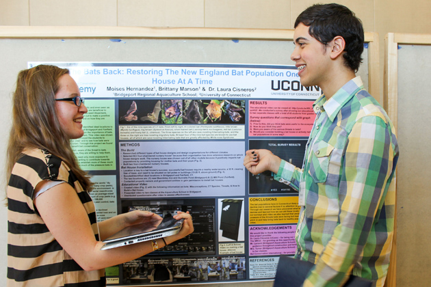 Brittany Marson, left, of Ludlow High School, and Moises Hernandez of Warren Harding High School, with their poster on efforts to restore the bat population. (Sheila Foran/UConn Photo)