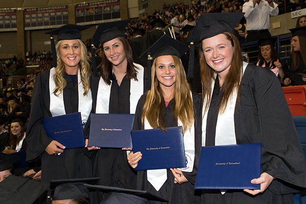 From left, Devon Mangle and Karson Ratliff (Volleyball), Chrissy Davidson and Chloe Hunnable (Field Hockey), all Class of 2015, holding their degree certificatesat Commencement in Gampel Pavilion. (Stephen Slade '89 (SFA) for UConn)