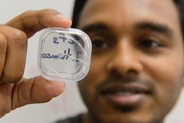 Sahan Handunkanda, a graduate student in physics, holds up a crystal of scandium trifluoride. (Peter Morenus/UConn Photo)